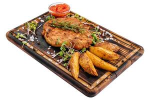 Grilled steak with baked potatoes on wood photo