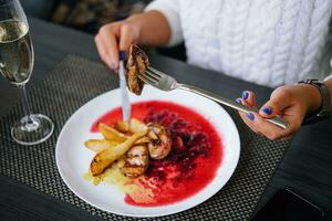 woman eating meat and drink champagne in a restaurant photo