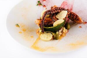 fried octopus with avocado on plate photo