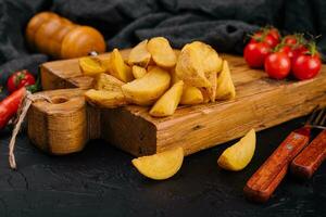Roasted potato wedges on wooden board photo