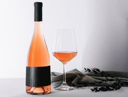 Glass and bottle of rose wine on light background photo