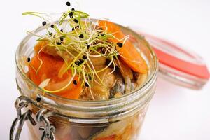 Slices of herring with spices in a glass jar photo