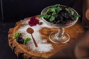 prunes in a glass bowl on a rustic wooden photo