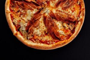 Pizza with jamon, cheese and mushrooms on black photo