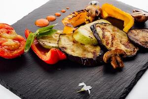 Assortment of grilled vegetables on dark wooden board photo