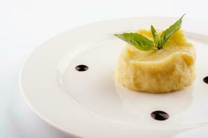 Mashed potatoes and basil on white plate photo