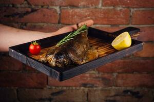 Delicious roasted fish with lemon on board photo