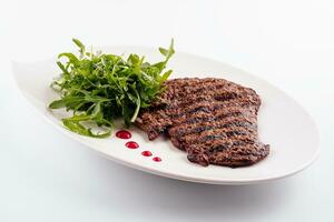 Ribeye steak with arugula on white plate photo