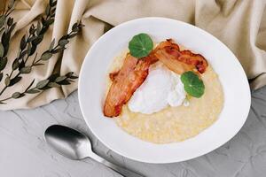 Savory oatmeal porridge with poached egg and bacon photo