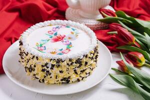 White cake decorated with cream near red tulips photo