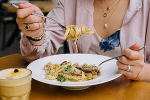 Woman Eating pasta with Mushrooms on wood table photo