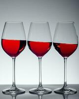 Series of three glasses of wine on gray background photo