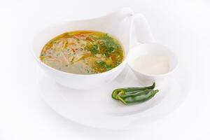 Chicken soup or broth with noodles, herbs and hot green pepper photo