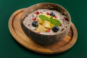 Healthy breakfast bowl with porridge with blueberries, pineapple and pomegranate photo