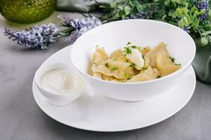 Delicious cooked dumplings and sour cream photo