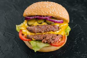 Double patty burger with pickles on black stone photo