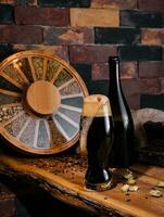 Glass of dark beer and bottle on wooden photo