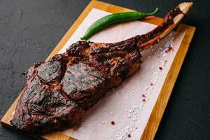 Freshly grilled Tomahawk steak on wooden cutting board photo