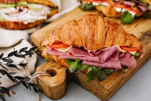 Delicious croissant sandwich on wooden board photo