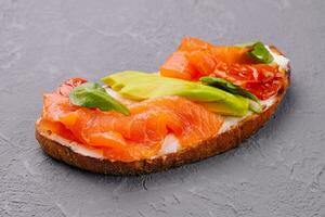 Homemade toast sandwich with salmon, avocado and basil photo