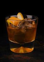 Old-fashioned cocktail with ice and orange peel photo