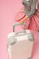 The doll carries a suitcase on wheels. Travel, vacation creative minimalistic concept photo