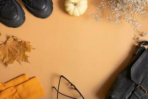 Woman's shoes with autumn leaves and pumpkin on orange background with copy space top view, flat lay photo