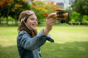 A little girl on vacation at the park with a pilot outfit and flying equipment. Run around and have fun with her dreams. photo