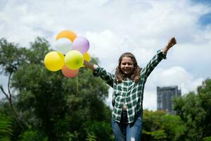 On a beautiful day in the park, a young girl enjoys her vacation. Playful with a red superhero costume and mask. photo