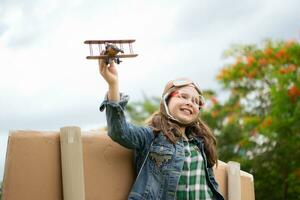 A little girl on vacation at the park with a pilot outfit and flying equipment. Run around and have fun with her dreams. photo