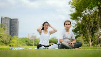 Young female and little girl with outdoor activities in the city park, Yoga is her chosen activity. photo