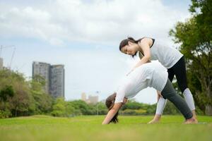 Young female and little girl with outdoor activities in the city park, Yoga is her chosen activity. photo