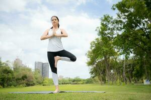 joven hembra con al aire libre ocupaciones en el ciudad parque, yoga es su elegido actividad. foto