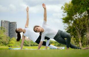 Young female and little girl with outdoor activities in the city park, Yoga is her chosen activity. photo