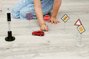 cute little girl playing at home on the floor with a typewriter, road signs and traffic lights photo