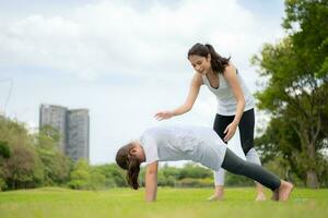 Young female and little girl with outdoor activities in the city park, Yoga is her chosen activity. photo