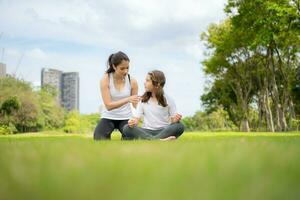 Young female and little girl with outdoor activities in the city park, Yoga is her chosen activity. photo