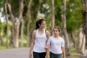 joven hembra y pequeño niña con caminando ejercicios en el ciudad parque foto