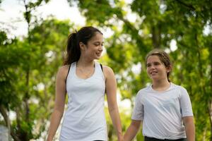 joven hembra y pequeño niña con caminando ejercicios en el ciudad parque foto