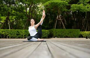 Young female on a wooden bridge in the park with healthy yoga activities photo