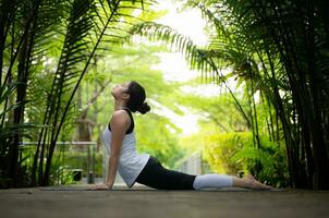 Young female in the garden there are wooden walkways and a tunnel of fresh green trees, with yoga activities for health photo