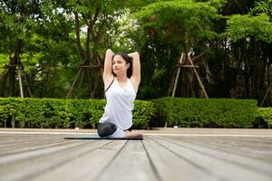 Young female on a wooden bridge in the park with healthy yoga activities photo