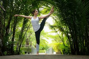 Young female in the garden there are wooden walkways and a tunnel of fresh green trees, with yoga activities for health photo