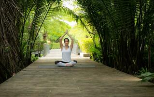 Young female in the garden there are wooden walkways and a tunnel of fresh green trees, with yoga activities for health photo