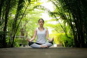 Young female in the garden there are wooden walkways and a tunnel of fresh green trees, with yoga activities for health photo