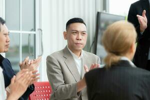 confidente asiático empresario sentado a silla y hablando con su colega en oficina foto
