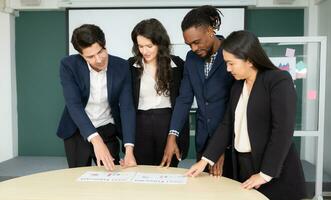 Group of business people discussing the charts and graphs showing the results of their successful teamwork photo