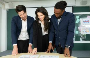 Group of business people discussing the charts and graphs showing the results of their successful teamwork photo