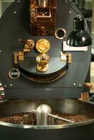 Coffee roaster machine with roasted coffee beans, close up photo