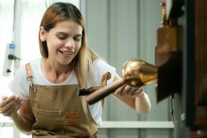 retrato de un joven mujer trabajando con un café tostador máquina foto